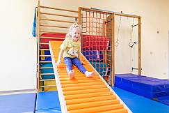Mädchen rutsch in der Turnhalle die Rollenrutsche herunter