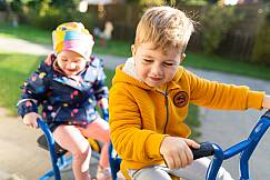 Zwei Kinder fahren gemeinsam auf einem Tretrad