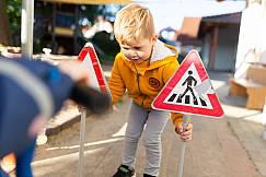 Junge spielt draußen mit Verkehrsschildern