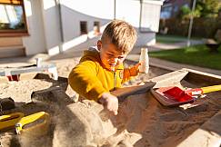 Junge spielt an Matschstation im Sand
